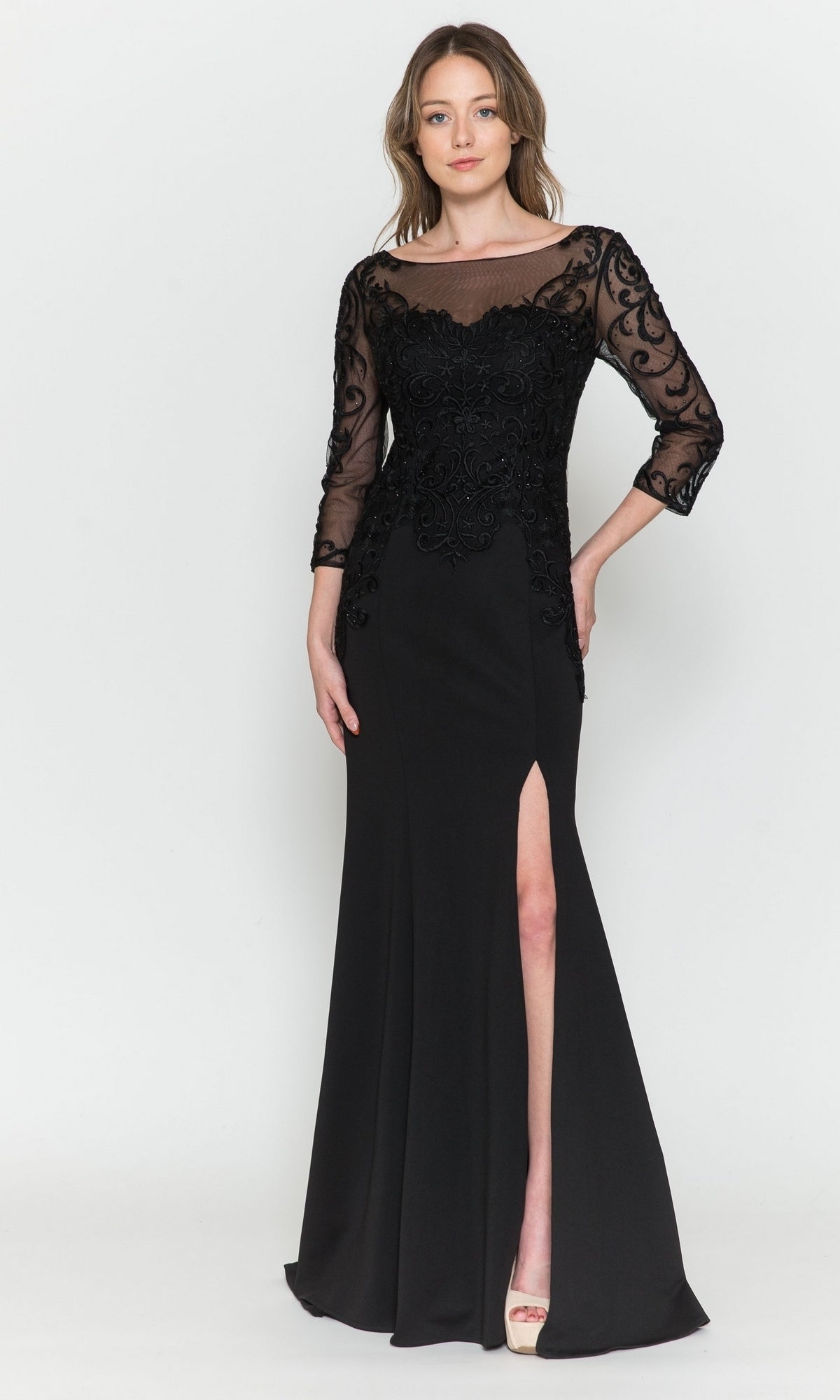 A woman models the black Embroidered Sheer-Sleeved Long Prom Dress 8564, featuring ornate bodice detailing and a thigh-high slit, against a plain light background.